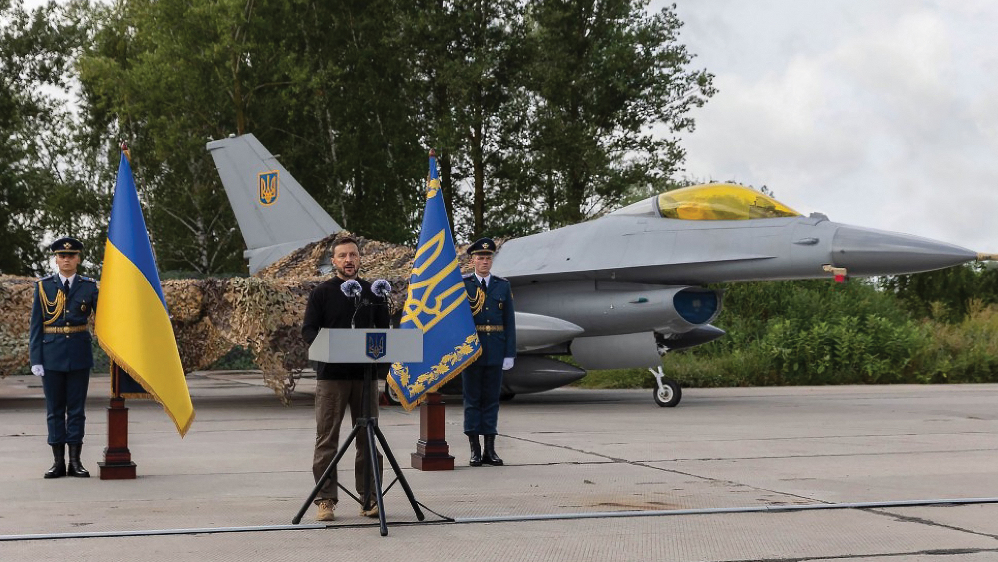 F-16 aircraft are already in Ukraine. This was announced by President Volodymyr Zelenskyy, center, at an undisclosed airbase while flanked by two F-16s on the Day of the Air Force of the Armed Forces of Ukraine, on August 4, 2024.  Zelenskyy noted that we are now at a new phase in the development of the Air Force of the AFU. Ukraine has done a lot to elevate the Ukrainian Air Force to a new standard of aviation – Western combat aviation.       Photo provided by the Office of the President of Ukraine